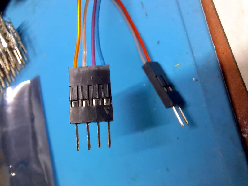 I due connettori Dupont completati: il connettore a quattro poli con i fili colorati dei segnali analogici (giallo, bianco, viola, e blu) e quello a due poli per l'alimentazione. I pin maschio sono ben visibili sul lato inferiore dei connettori